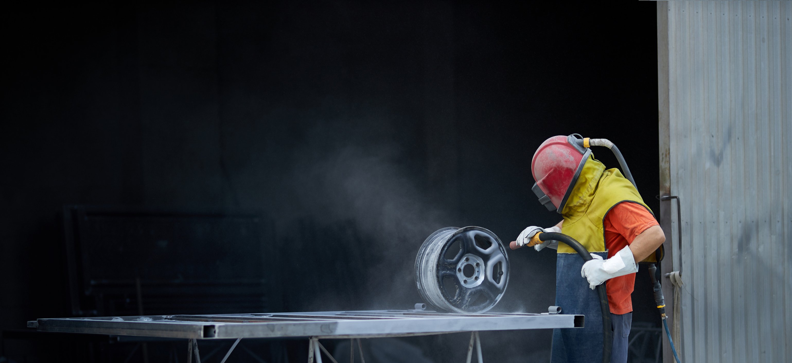 Man Using Sandblaster for Cleaning Metal Details at Work